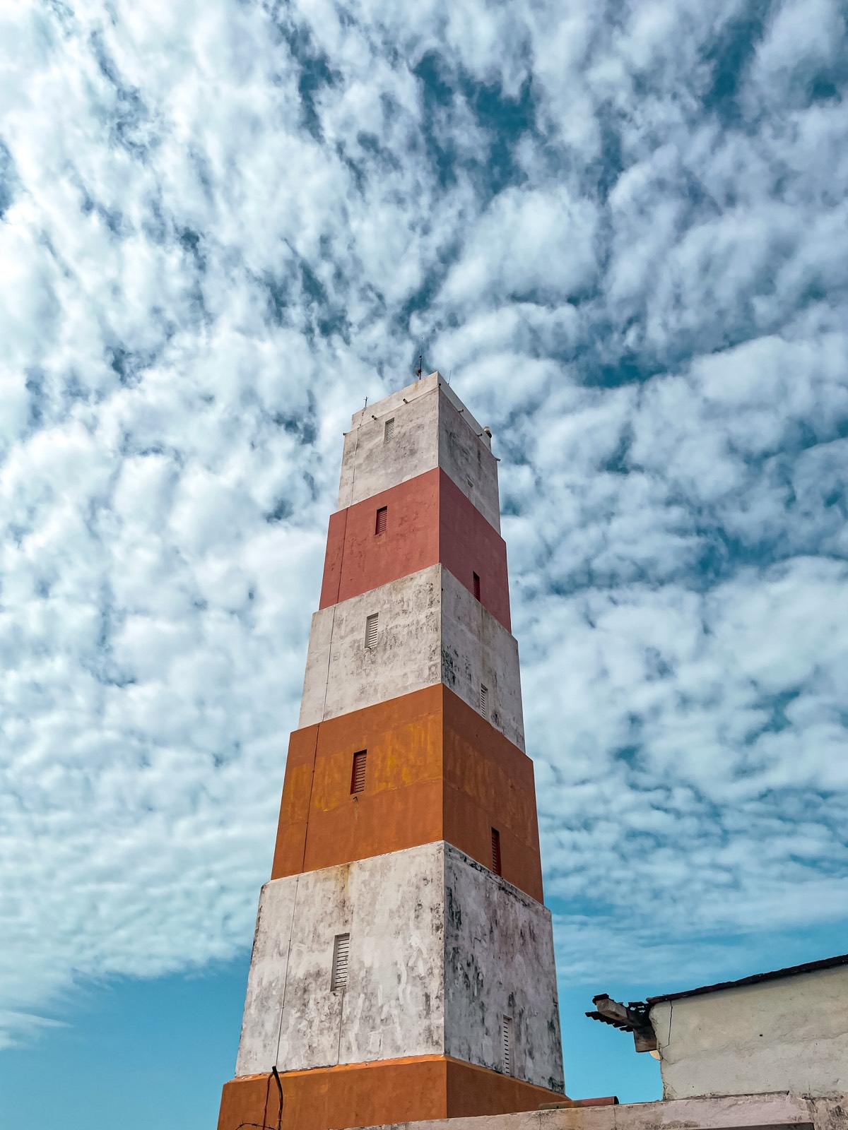 Striped tower against cloudy sky